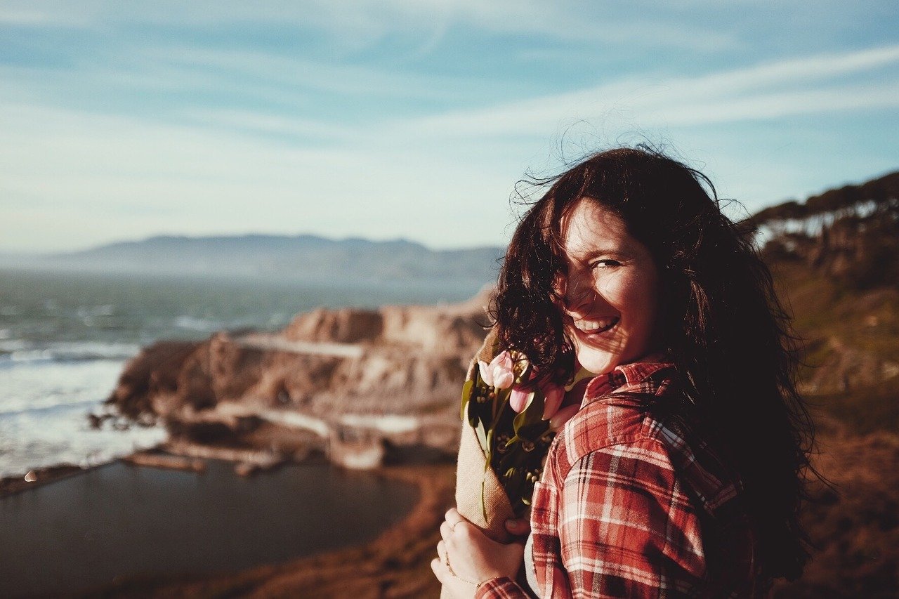 Woman smiling - Your emotional health is critical in influencing your physical health - let’s discuss the best ways to recharge your emotional wellness!