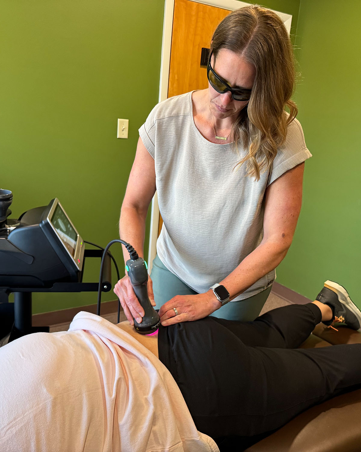 Dr. Kerstin Zock DC using laser therapy on a patients back